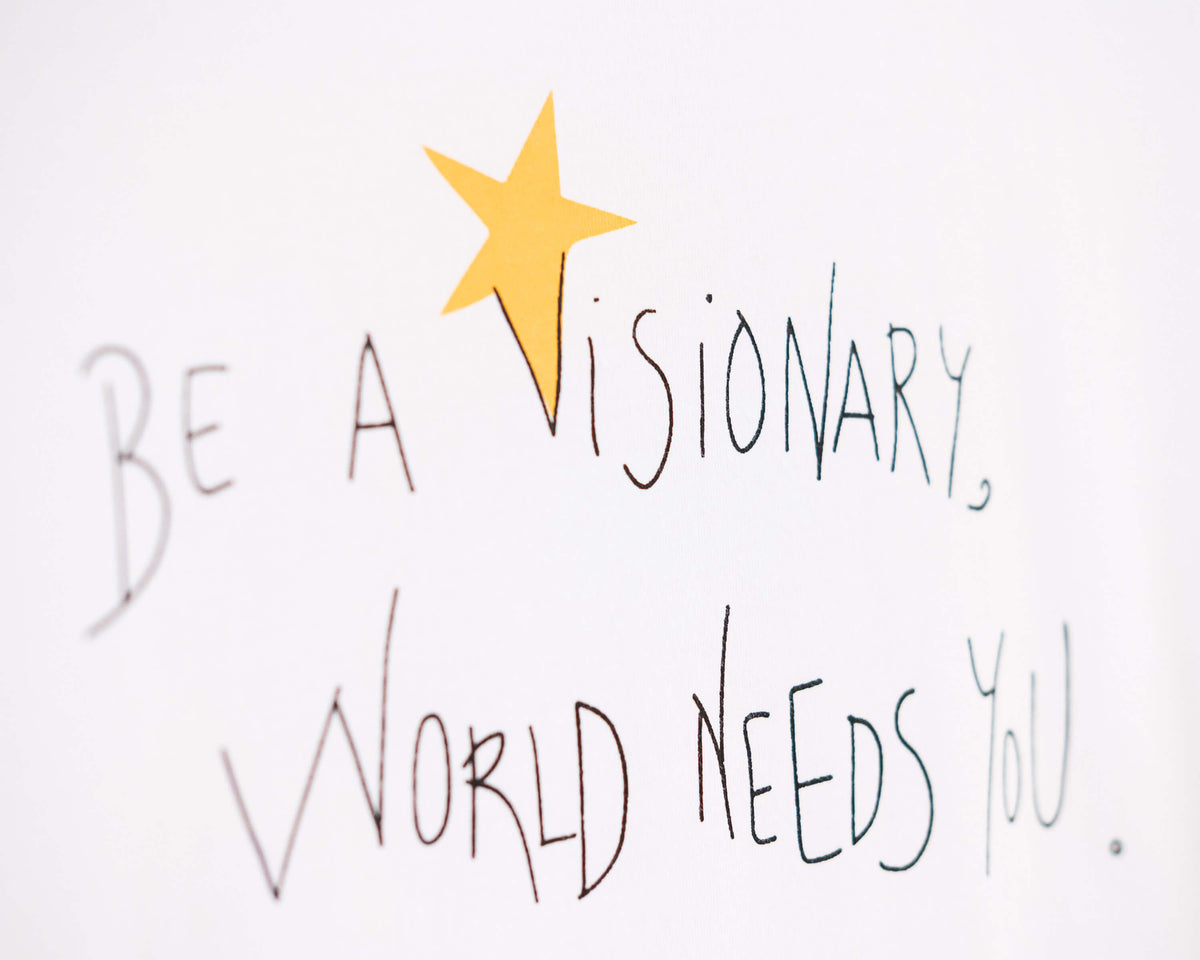 Detalle de texto serigrafía en color negro, y amarillo. Camiseta blanca de mujer, de algodón orgánico y estampado a mano con tintas ecológicas.