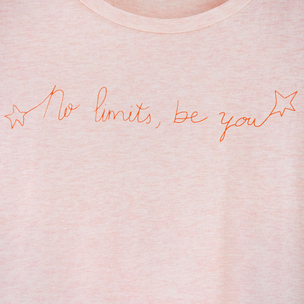 Detalle de texto estampado en color naranja. Camiseta rosa de mujer, de algodón orgánico y estampada a mano con tintas ecológicas.