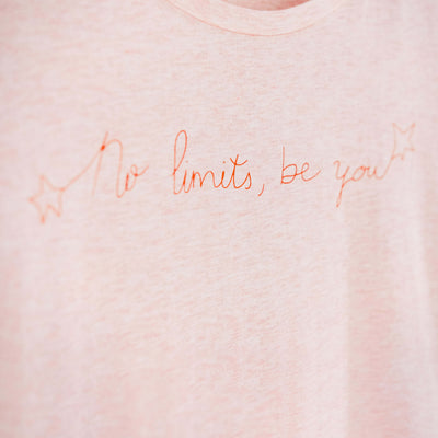 Detalle de texto estampado en color naranja. Camiseta rosa de mujer, de algodón orgánico y estampada a mano con tintas ecológicas.