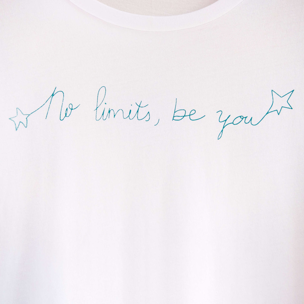 Detalle de texto estampado en color azul. Camiseta blanca de mujer, de algodón orgánico y etampada a mano con tintas ecológicas.