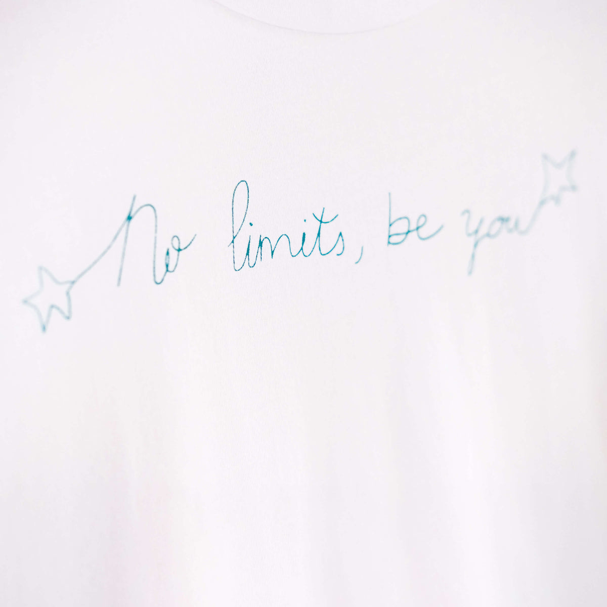 Detalle de texto estampado en color azul. Camiseta blanca de mujer, de algodón orgánico y etampada a mano con tintas ecológicas.