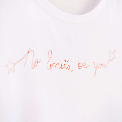 Detalle de texto estampado en color naranja. Camiseta blanca de mujer, de algodón orgánico y estampada a mano con tintas ecológicas.