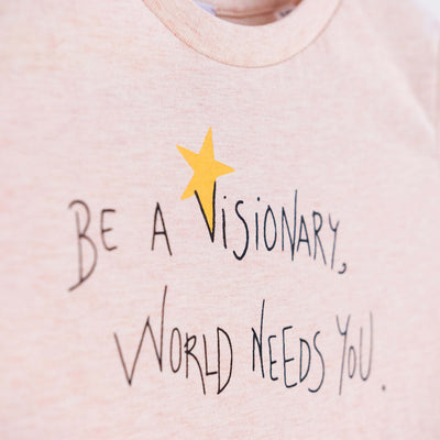 Detalle de texto serigrafía en color negro, y amarillo. Camiseta rosa de algodón orgánico para niños, estampado a mano con tintas ecológicas. Modelo unisex.