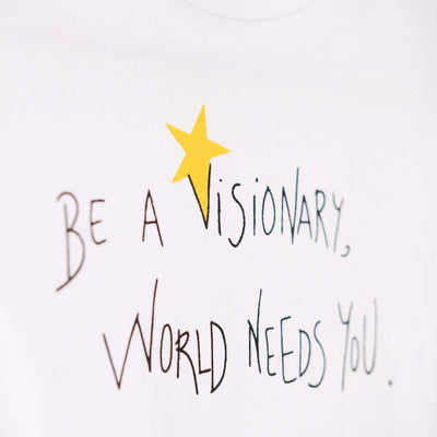 Detalle de texto serigrafía en color negro, y amarillo. Camiseta blanca de algodón orgánico para niños, estampado a mano con tintas ecológicas. Modelo unisex.