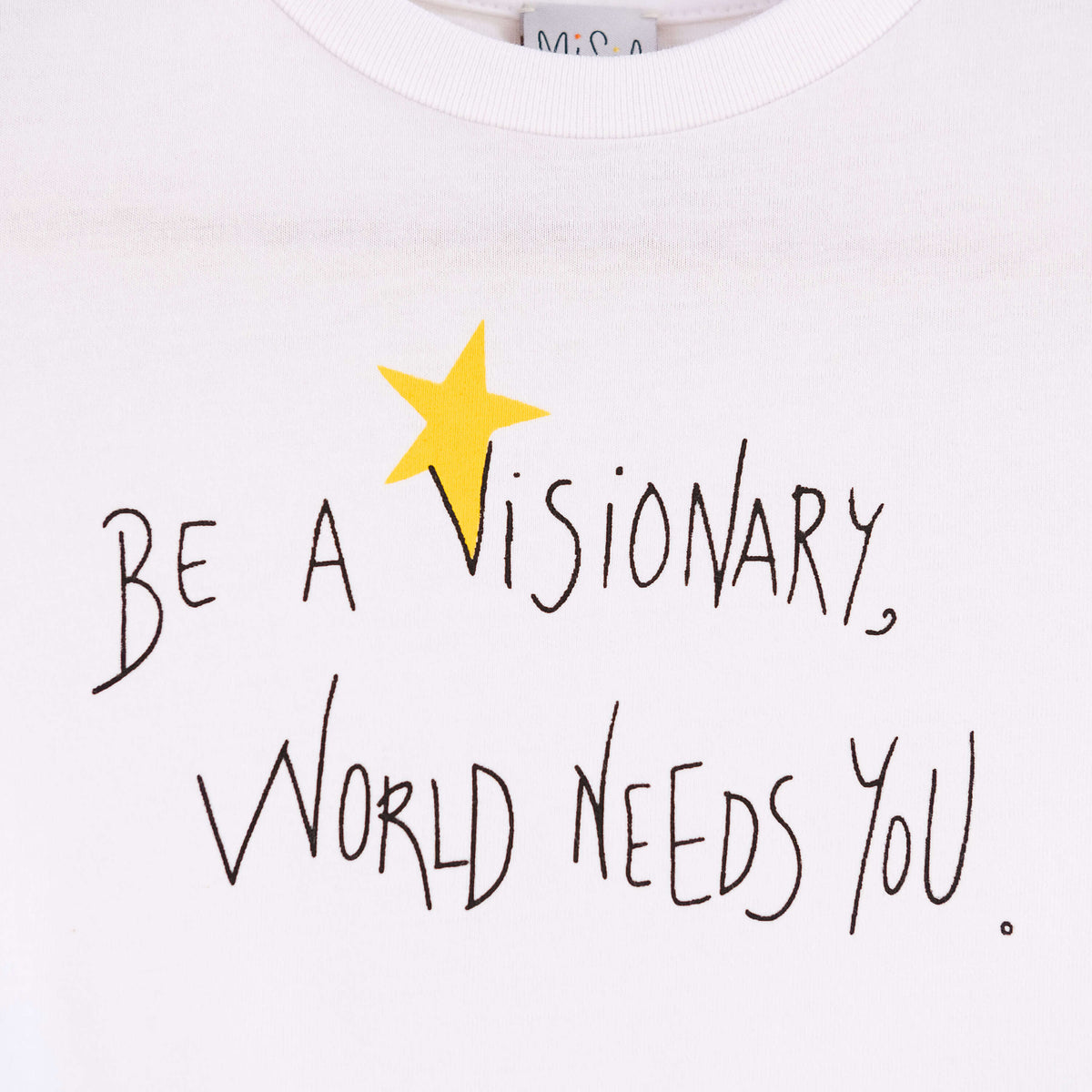 Detalle de texto serigrafía en color negro, y amarillo. Camiseta blanca de algodón orgánico para niños, estampado a mano con tintas ecológicas. Modelo unisex.