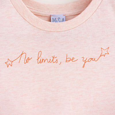 Detalle de texto estampado en color naranja. Camiseta rosa de algodón orgánico para niños, estampado a mano con tintas ecológicas. Modelo unisex.