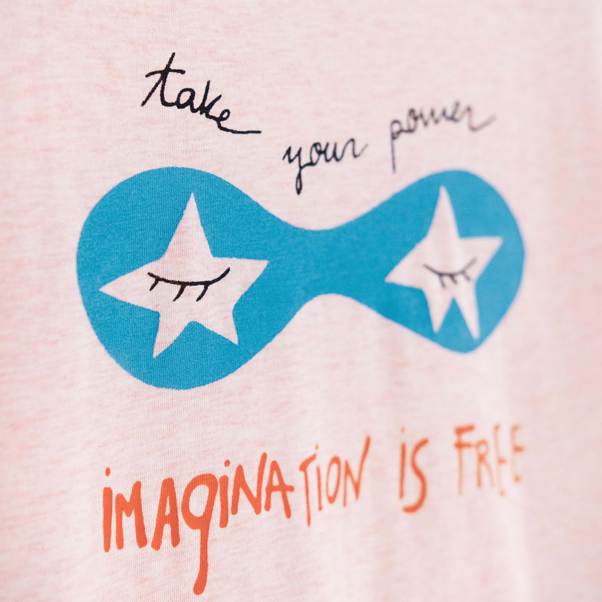 Detalle de texto serigrafía en color negro, azul y naranja. Camiseta rosa de mujer, de algodón orgánico y estampado a mano con tintas ecológicas.